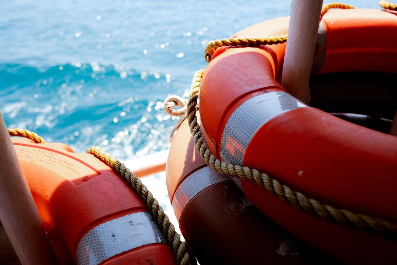 A detailed image of orange lifebuoys and ropes aboard a vessel on the ocean waves.
